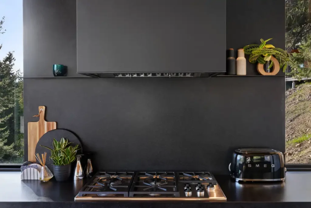 Kitchen at Basking Moose featuring black honed granite countertops, a Wolf cooktop, and steel accent shelves.