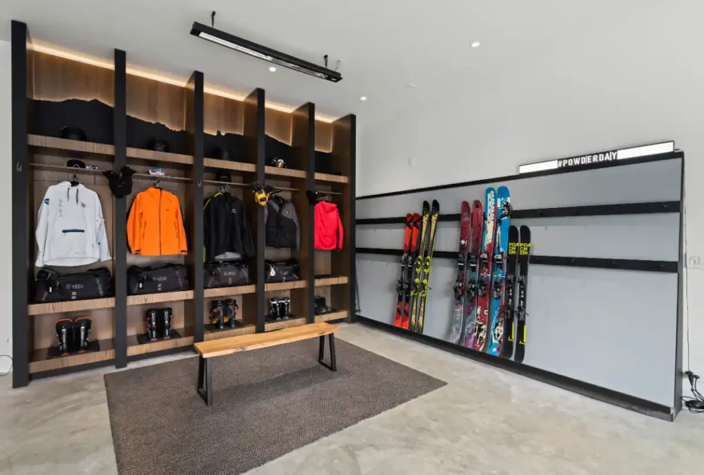 Ski gear room at Basking Moose with open wood lockers, wall-mounted ski racks, and a bench for putting on boots.