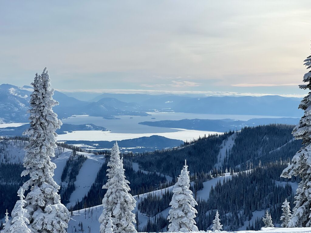 View from Schweitzer Mountain overlooking snow-covered forest and Lake Pend Oreille in North Idaho, highlighting the landscape that shapes how homes are thoughtfully built in the region.