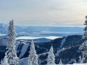 View from Schweitzer Mountain overlooking snow-covered forest and Lake Pend Oreille in North Idaho, highlighting the landscape that shapes how homes are thoughtfully built in the region.