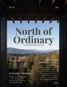 Cover of North of Ordinary | The Smithwright Journal, Vol. 01. The image looks through a modern mountain home's covered outdoor living space toward a panoramic view of Lake Pend Oreille, forested hillsides, and distant snow-capped mountains. The journal cover features article highlights including The Edge, Screamin' Marmot, and Building with Confidence, Living with Intention, alongside the Smithwright logo and the year 2026.